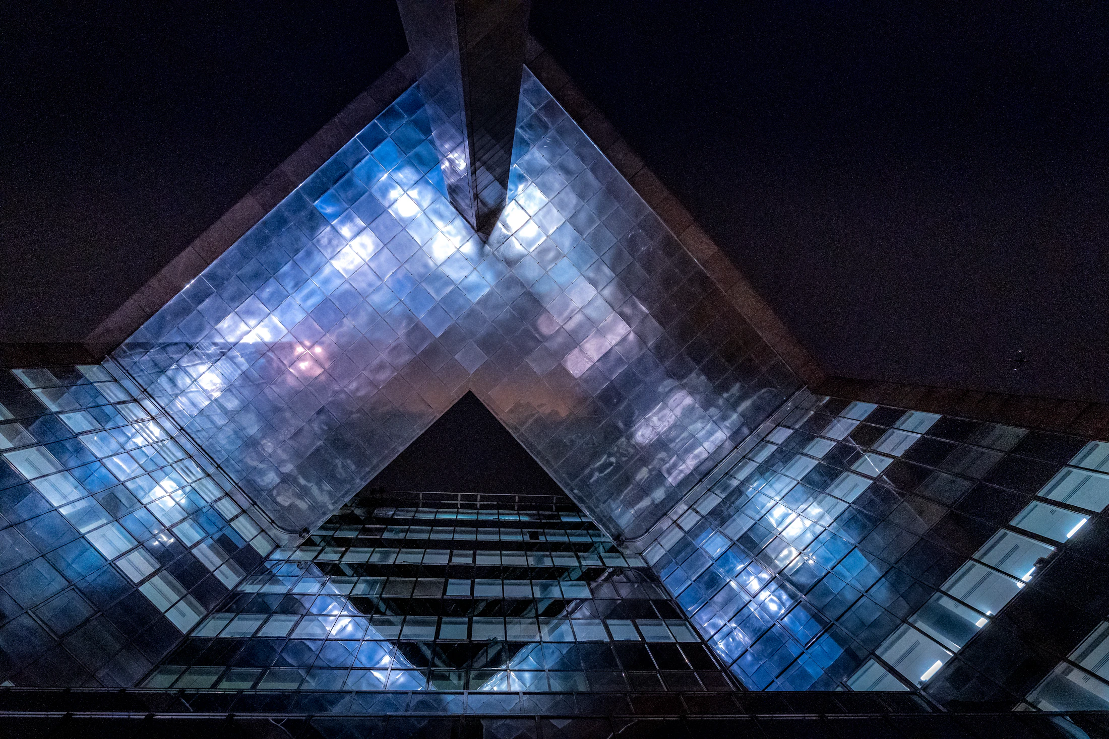 A complex glass building forming one coherent structure at night
